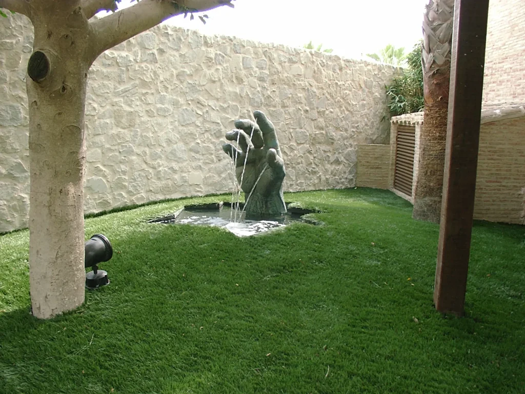 Jardín mediterráneo con fuente ornamental y césped en Orihuela Playa
