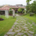 Camino de piedra entre césped y pérgolas en jardín residencial