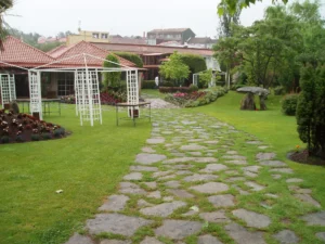 Camino de piedra entre césped y pérgolas en jardín residencial
