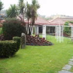 Jardín residencial con césped natural y pérgolas blancas
