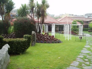 Jardín residencial con césped natural y pérgolas blancas