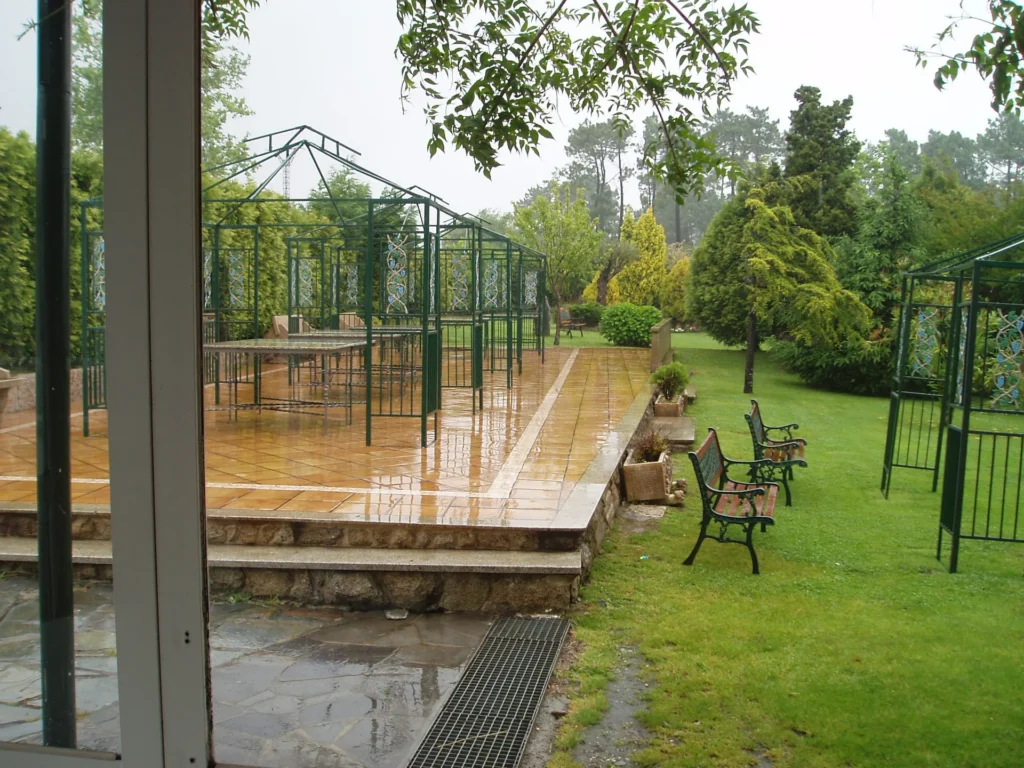 Terraza exterior con pérgolas y bancos junto al jardín